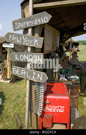 World War II replica signs to New York, London, Berlin and Shirley with mileage totals in front of tents Stock Photo