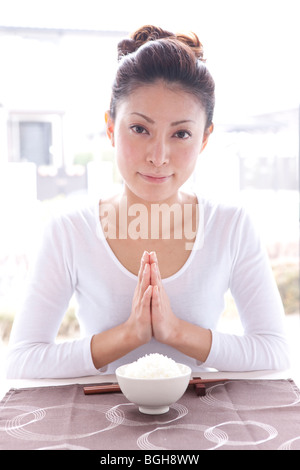 Young Woman at Table with Praying Hands Stock Photo