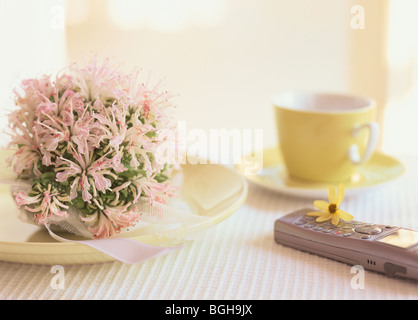 Mobile phone on table next to flowers and coffee cup Stock Photo