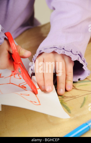 Stock photo of a four year old girl cutting out a picture she has just drawn on a piece of paper. Stock Photo