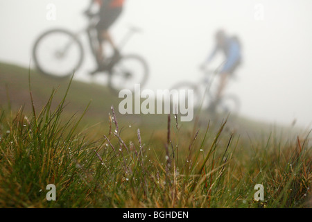 Two mountain bikers ride a misty trail at Howgill Fells, United Kingdom Stock Photo