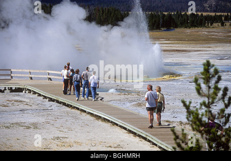 Tourists walk through a geyser basin near Old Faithful, in Yellowstone National Park Stock Photo