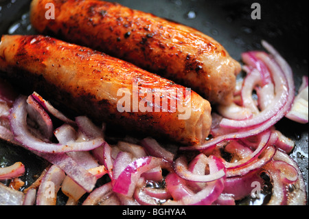 Sausages & onions frying in pan Stock Photo