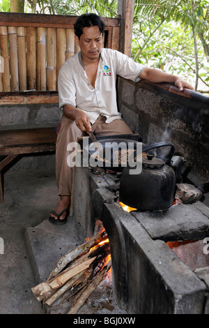 Balinese man roasting coffee beans. Focus is on the beans in the pan. Stock Photo