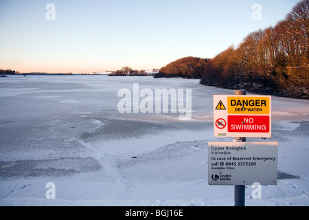 Danger Deep Water No Swimming notice, Upper Rivington Reservoir covered in snow, Lever Park, Horwich, Greater Manchester, UK Stock Photo