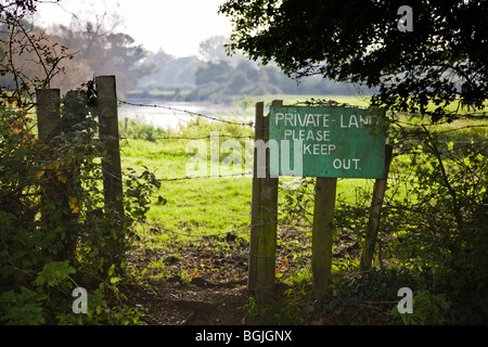 Fence and notice marking a boundary. Sign reads 'Private Land Please Keep Out'. Borders of Hampshire and Dorset, UK. Stock Photo