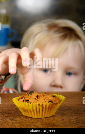 Stock photo of a little girl looking longingly at a cake on the kitchen table. Stock Photo