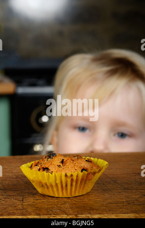 Stock photo of a little girl looking longingly at a cake on the kitchen table. Stock Photo