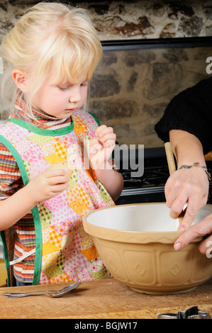 Stock photo of a four year old girl cracking eggs into a mixing bowl ready to make some cookies. Stock Photo