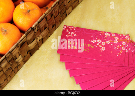 Chinese New Year money packets with a box of Mandarin Oranges by the side Stock Photo