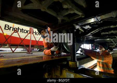 Two workmates at the Brighton and Hove bus company depot fit snow chains to the wheels of a bus during a cold snap in January. Stock Photo