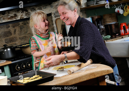 Stock photo of a four year old girl and her mother baking cookies together in the kitchen. Stock Photo