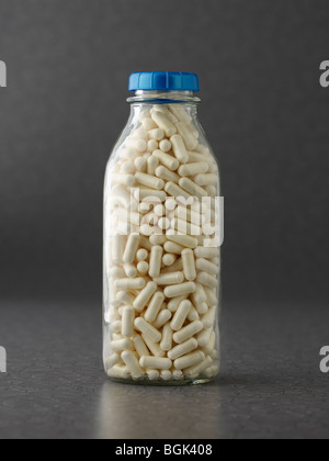 Milk protein capsules in milk bottle on gray background Stock Photo