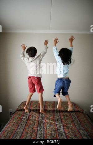 Brother and sister bounce on bed Stock Photo