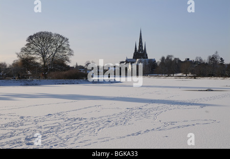 Three spires cathedral and frozen Stowe Pool with footprints across the on snowy winter’s day 2010 Lichfield England Stock Photo