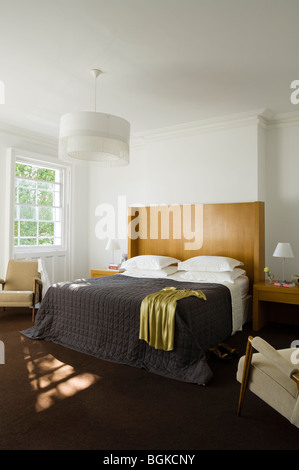 Double bedroom with black quilt and white lightshade Stock Photo
