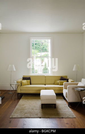 Sitting room yellow sofa, ottoman and rug Stock Photo