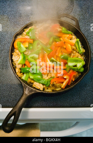 Chicken Fajitas cooking in a iron skillet on a stove top. Stock Photo