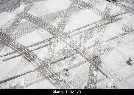 Abstract tyre (tire) tread tracks are left as abstract patterns in melting snow after bad weather in a supermarket car park. Stock Photo