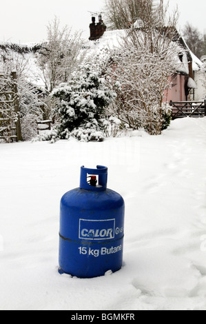 Butane cylinder bottle standing in snow during Winter.Home heating delivery Stock Photo
