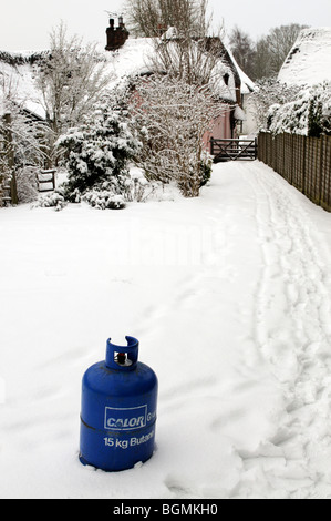 Butane cylinder bottle standing in snow during Winter.Home heating delivery Stock Photo