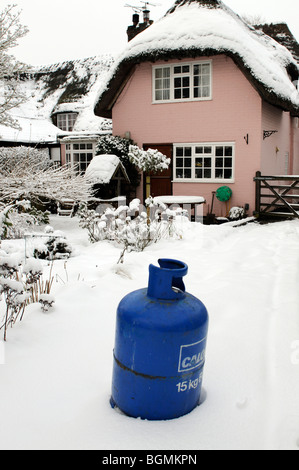 Butane cylinder bottle standing in snow during Winter.Home heating Stock Photo