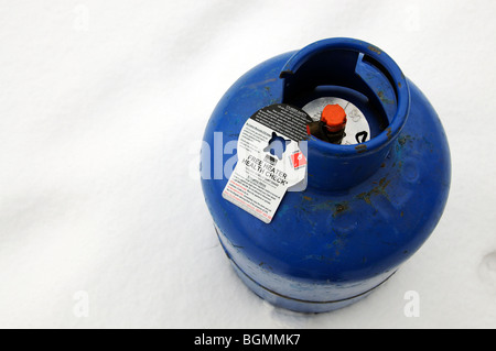 Butane gas cylinder bottle standing in snow with a free heater health check notice attached Stock Photo