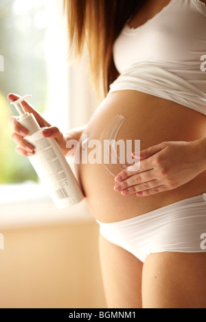 Pregnant woman applying cream Stock Photo