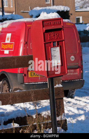 A Royal Mail delivery van parked next to a snow topped Queen Elizabeth II Lamp Box, Buckinghamshire, England, United Kingdom. Stock Photo