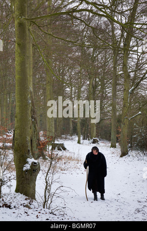 A woman walks through a cold snow covered woodland. Stock Photo