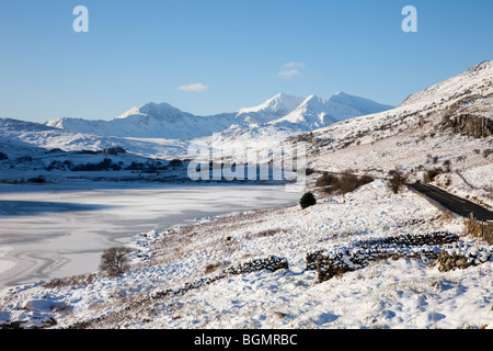 Snowdonia landscape in winter view across Llynnau Mymbyr frozen lakes to Snowdon horseshoe peaks in Snowdonia National Park with snow. North Wales UK Stock Photo