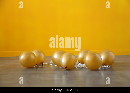 gold balloons sink to the floor after the party deflated Stock Photo