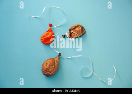 deflated balloons with white ribbon on blue floor Stock Photo