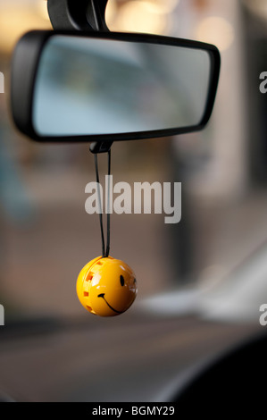 Smiley face air freshener hanging from rear view mirror Stock Photo