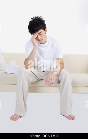 Young man having headache and frowning Stock Photo