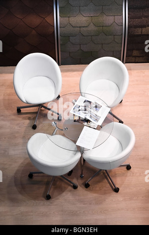 Four white chairs and glass round table in room. Interior of speaking place Stock Photo