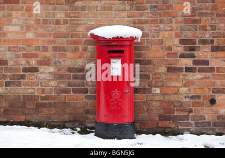 A traditional red pillar box covered in snow in Worcester, UK Stock Photo