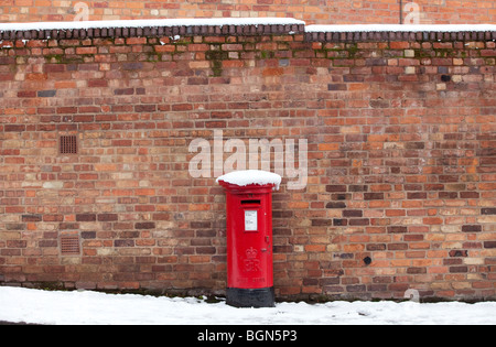 A traditional red pillar box covered in snow in Worcester, UK Stock Photo