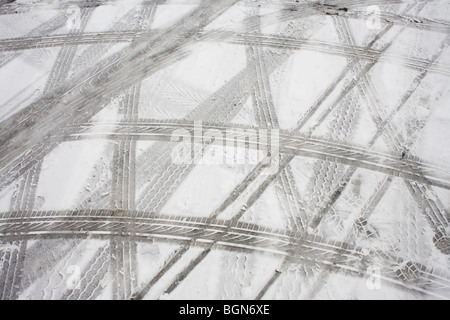 Abstract tyre (tire) tread tracks are left as abstract patterns in melting snow after bad weather in a supermarket car park. Stock Photo