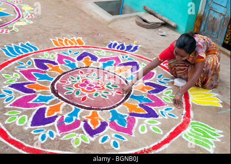 Indian woman making a Rangoli festival design in an Indian street at the hindu festival of Sankranthi. Puttaparthi, Andhra Pradesh, India Stock Photo