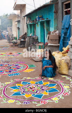 Indian woman making a Rangoli design in an Indian street during the hindu festival of Sankranthi. Puttaparthi, Andhra Pradesh, India Stock Photo