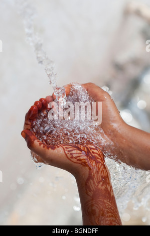 Indian childs cupped hands catching poured water. India Stock Photo