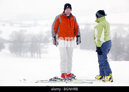 Two people, a man and a woman dressed in ski clothing, chatting on a snowy hillside Stock Photo