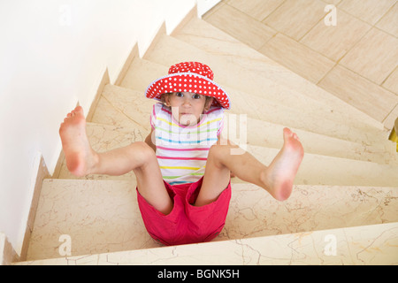 young smiling caucasian girl wearing Panama fall from stairs Stock Photo