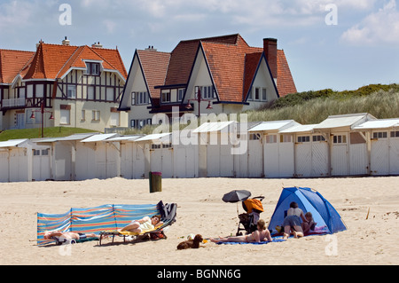 Sunbathers on beach and houses in Belle Époque style of the consession at seaside resort De Haan, West Flanders, Belgium Stock Photo