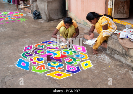 Indian sisters making a rangoli design outside there home during the hindu festival of Sankranti. Puttaparthi, Andhra Pradesh, India Stock Photo