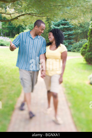 Mid adult man holding hands of a young woman and walking in a lawn Stock Photo