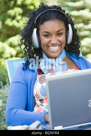 Portrait of a young woman wearing headphones and using a laptop Stock Photo