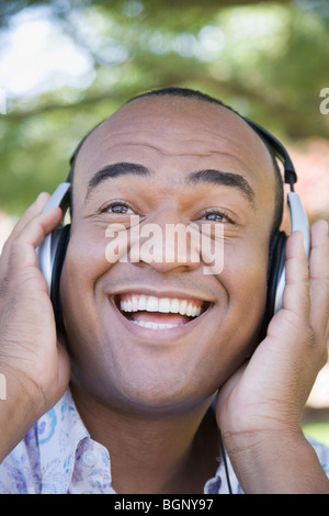 Close-up of a mid adult man wearing headphones and listening to music and smiling Stock Photo