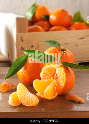 Fresh whole clamentines and segments with a box of clamentines in a kitchen setting Stock Photo